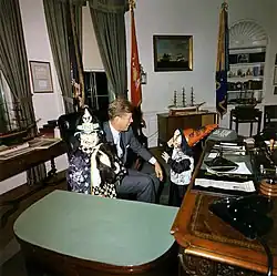 Návštěvníci během Halloweenu u prezidenta, americký prezident John F. Kennedy se svými dvěma dětmi v halloweenských kostýmech. Prezident Kennedy, John F. Kennedy junior, Caroline Kennedyová. Bílý dům, Oválná pracovna, 31. října 1963.