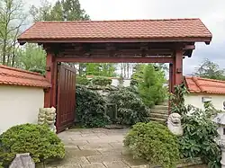 Vstupní brána do zahrady strážená dvojicí lev a lvice, v pozadí brány je omývací studánka