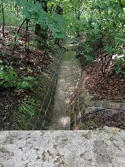 Dočasně zavodněné koryto potoka poblíž ulice Pod Vavřincem je lemované starými duby