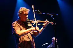 Muž v košili hrající na elektrickou violu