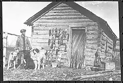 John Hornby and some of his dogs in front of one of his remote trapping cabing, in the NWT