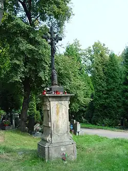 Kříž přenesený ze zaniklé obce Slatinice na starý hřbitov v Mostě. Na pískovcové patě kříže je vytesána dedikace sv. Šimonu a Judovi.