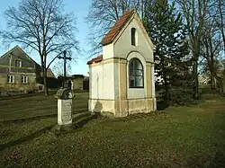Výklenková kaplička sv. Jana Nepomuckého s křížem ve spodní části návsi