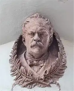 busta na domě firmy v Praze (1886)