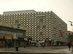 Barevná fotografie s pohledem na moderní budovu s plastickým geometrizujícím obložením