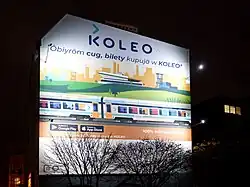 Reklamní billboard ve slezštině s nápisem „Vybírám si vlak a kupuji si jízdenky v Koleu!“