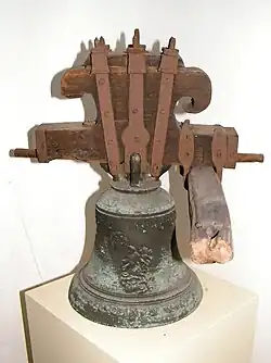 Sanktusový zvon připevněný k dřevěné hlavě