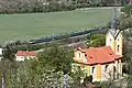 Výhled na kostel sv. Václava a železniční hradlo Horní Mokropsy, které právě minul spoj SC 511 Pendolino
