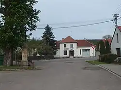 Náves s křížem z roku 1903 a hospodou