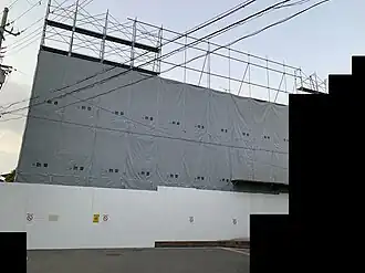 Budova studia je zahalena lešením a bílou plachtou, která tak zakrývá demoliční práce