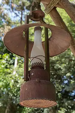 Rezavá petrolejová lampa zavěšená na dřevěné konstrukci