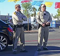 Dva policisté v hnědých uniformách u osobního automobilu