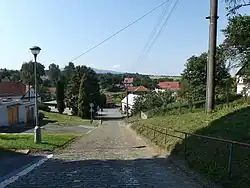 Svažitá boční ulice, kolem které je soustředěna podstatná část zástavby vesnice. Doleva výjezd na Kelč, doprava na Babice. V pozadí Kelčský Javorník.