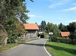 Západní okraj vesnické památkové rezervace. Na snímku vlevo je památkově chráněný roubený dům čp. 14.