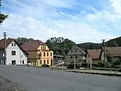 Náves ve Lhotce, v pozadí uprostřed komunitní centrum a místní hostinec