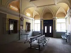 Pohled do typické současné čekárny ve stanici ATE, na litoměřickém horním nádraží. Dominuje jí strop s klenbami a řada laviček pro čekání cestujících. Na levé straně se pak nacházejí dvě okna osobních pokladen.