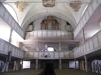 Dvoupatrová empora nad hlavní lodí, v druhém jejím patře umístěny varhany, na stropě fresky a na podlaze lodi stojící lavice