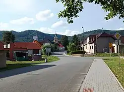 Střed vsi s kostelem svatého Karla Boromejského, v pozadí Oderské vrchy