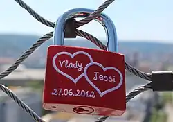 Červený zámek s namalovanými jmény páru v srdíčkách a datem zamčení