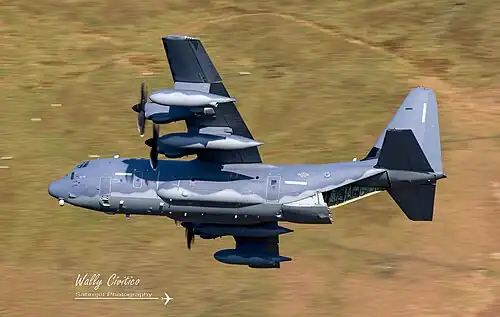 Lockheed MC-130 Hercules speciálních jednotek Letectva Spojených států s otevřenou nakládací rampou, na které sedí členové osádky, 2022