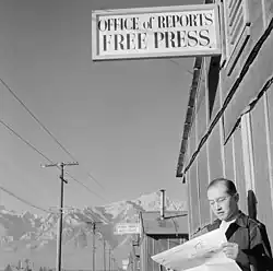 Roy Takeno čte před kanceláří redakce v táboře výtisk Manzanar Free Press