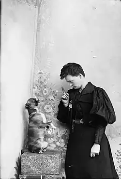 Marie Hoeg vztyčuje ukazováček na psa jménem Tuss, asi 1895–1903