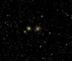 Simulace přechodu Marsu a Saturnu přes Jesličky. Uprostřed jsou vidět desítky členů hvězdokupy, mezi nimi jasně září načervenalý Mars a vlevo od hvězdokupy žlutě svítí Saturn.