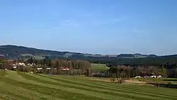 Vrchovinou obklopená obec Křižánky, pohled ze svahu vrchu Na borovině v Milovské kotlině, georeliéfem sníženině v rozsahu 588 až 674 m n. m. tvořící geomorfologický okrsek