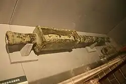 Fotogragie dosti zašlé cca půl metru dlouhé bronzové hlavně, ležící v muzejní vitríně.