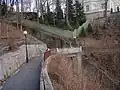 Lávka na stezce Jeane de Carro přes betonový zářez nedokončené lanovky, březen 2011