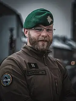 Fotografie zobrazuje Ondřeje Havlíčka oděného do vojenské uniformy vz. 95 Armády České republiky. Má na sobě tmavě zelený baret, který je typický pro příslušníky Informačních a kybernetických sil Armády ČR. Na pravém rukávu uniformy je viditelná nášivka s logem Informačních a kybernetických sil Armády ČR, což odkazuje na Havlíčkovo působení v této složce.