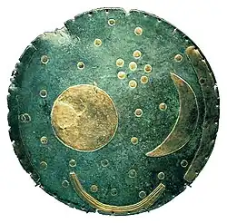 Nazelenalý bronzový kotouč s pozlacenými tvary Slunce, Měsíce a hvězd. Na okraji jsou tři zlaté oblouky. Skupinka sedmi hvězd uprostřed představuje Plejády.