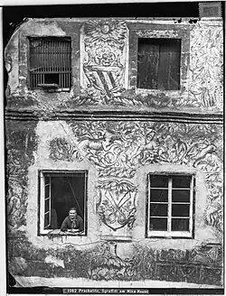 Neumannova čp. 144, detail sgrafit, vlk, vlk s ptákem v tlamě, zajíc žene jednorožce, Rožmberský erb. Fotografie byla pořízena pravděpodobně skupinou pod vedenín Friedricha von Shmidta v roce 1884 (Josef Wlha, https://digital.onb.ac.at/rep/osd/?132044E5)