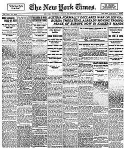 Černobílá fotografie titulní strany novin The New York Times z 29. července 1914. Hlavní titulek na stránce hlásá "AUSTRIA FORMALLY DECLARES WAR ON SERVIA; RUSSIA THREATENS, ALREADY MOVING TROOPS; PEACE OF EUROPE NOW IN KAISER'S HANDS". Stránka je plná textu rozděleného do sloupců s různými články a zprávami, které poskytují informace o tehdejších světových událostech.