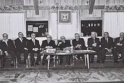 Členové druhé vlády Leviho Eškola v domě prezidenta Zalmana Šazara v Jeruzalémě. Zleva doprava: Jisra'el Bar Jehuda, Josef Burg, Dov Josef, Levi Eškol, prezident Zalman Šazar, Chajim-Moše Šapira, Bechor-Šalom Šitrit, Josef Almogi, Akiva Govrin.