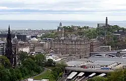 Pohled z edinburského hradu k severovýchodu na Calton Hill a zátoku Firth of Forth. V popředí je hlavní nádraží Waverley Station a budova skotského parlamentu.