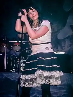 Zpěvačka Anette Olzon opírající se o mikrofon a jeho stojan během vystoupení v roce 2008.