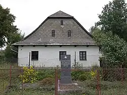 pomník partyzána M.V. Barjačného před domem čp. 11