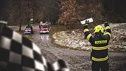 Fotografie zachycuje Ondřeje Havlíčka v hasičské uniformě, jak startuje netradiční závod mezi cisternovou automobilovou stříkačkou jednotky sboru dobrovolných hasičů obce Pavlov a speciální hasičskou čtyřkolkou. Fotografie vznikla během natáčení videa o dobrovolných hasičích.