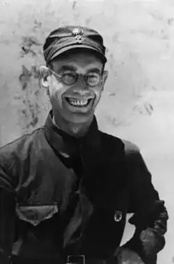 Fotografie muže středního věku s širokým úsměvem, brýlemi, čepicí s kšiltem, v tmavé blůze