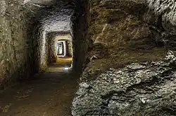 Barevná fotografie; mohutná chodba přeskačského podzemí vytesaná do kamenného masivu