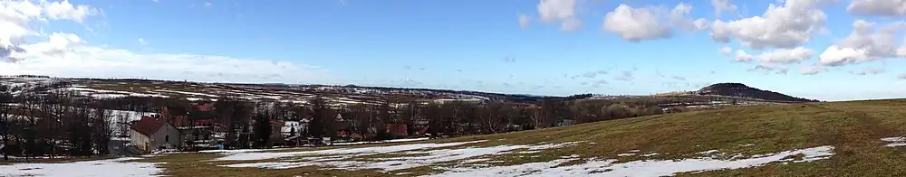 Pohled na část Krásného Lesa a vrch Špičák (vpravo), který je se 723 m n. m. druhým nejvyšším bodem katastrálního území. Pod Špičákem je vidět část dálnice D8.