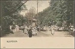 Pohled na osoby sedící u několika stolů v zahradní restauraci.