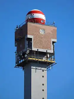 Horní konec čtvercové věže s červeno-bíle pruhovanou kulovou nástavbou