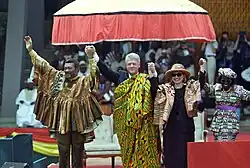 Prezident Bill Clinton, první dáma Hillary Rodham Clintonová, prezident Jerry John Rawlings a jeho manželka Nana Konadu Agyeman Rawlings společně zvedají ruce na pódiu v Akkře, Ghana.