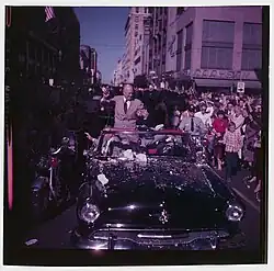 Prezidentský kandidát Dwight Eisenhower sedí na kabrioletu v průvodu procházejícím ulicí města