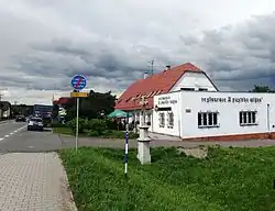 Restaurace při hlavní silnici, směr Krnov. V popředí kříž s německým nápisem.