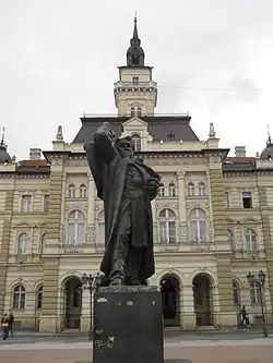 Socha s budovou magistrátu města Novi Sad v pozadí