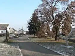 Náves v Rájci, vpravo v popředí smírčí kříž ze 16. století