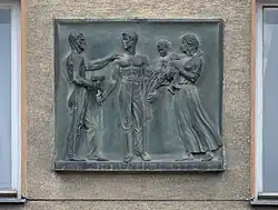 Reliéf od Leopold Hohl, sedlák se bratří s dělníkem a vedle stojící matka s dítětem, r. 1938 (Wien, Schlachthausgasse 44)